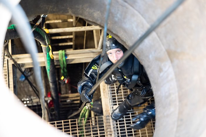 En dykare i Sveatunneln som tittar upp genom en tunnel.