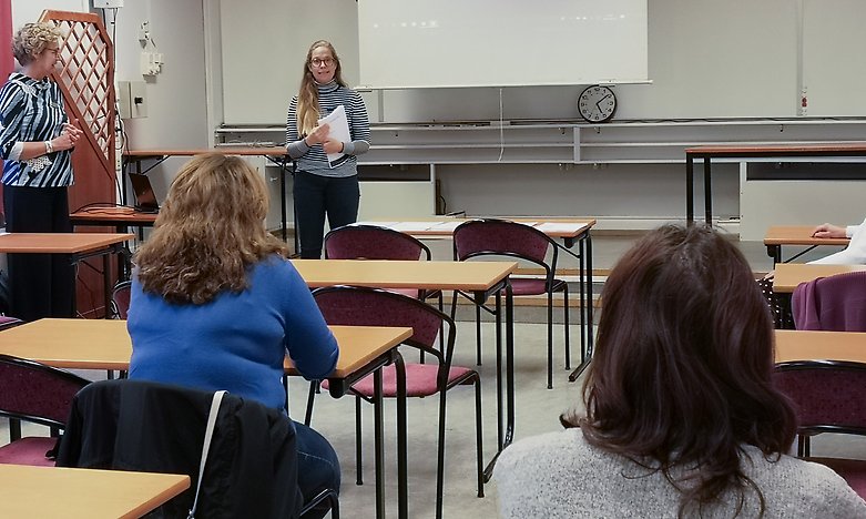 Kvinna pratar framför personer i ett klassrum