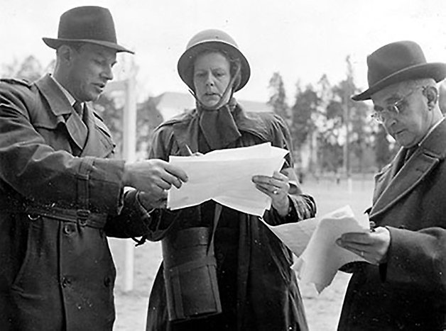 Märta Bergqvist och två män läser på papper