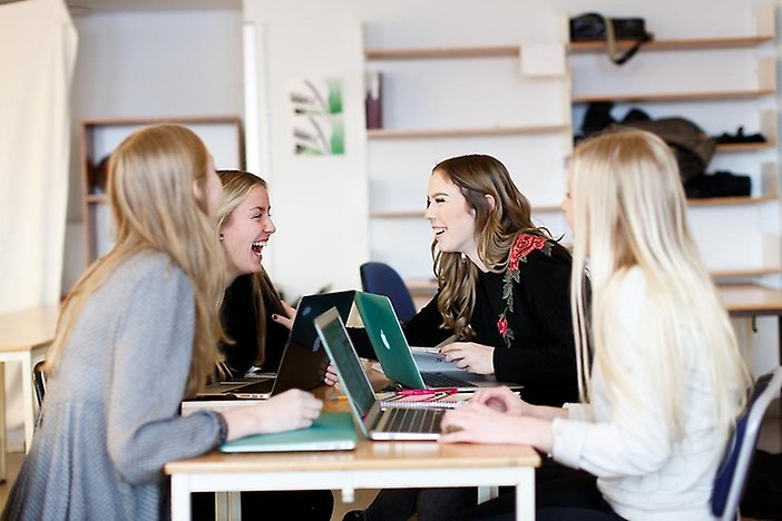Fyra glada gymnasieelever pluggar med varsin dator.